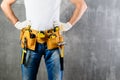 unknown handyman with hands on waist and tool belt with construction tools against grey background with copyspace for text. DIY t Royalty Free Stock Photo