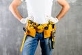 unknown handyman with hands on waist and tool belt with construction tools against grey background. DIY tools and manual work con Royalty Free Stock Photo