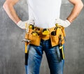 unknown handyman with hands on waist and tool belt with construction tools against grey background. DIY tools and manual work con Royalty Free Stock Photo