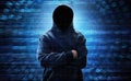 Hooded computer hacker standing over binary code