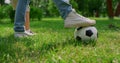 Unknown human legs kicking ball on grass closeup. Father play football with son.