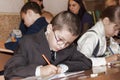An unknown junior student at a desk writes something in a notebook at a lesson in one of the schools in Sloviansk