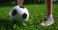 Unknown kids feet playing football on grass close up. Boy legs kick ball in park Royalty Free Stock Photo