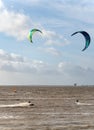 Unknown kitesurfers surf on brown water with waves from the Atlantic