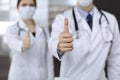 Unknown man-doctor and woman standing straight as a team and showing Ok sign with thumbs up in modern clinic. Medicine Royalty Free Stock Photo