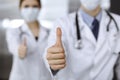 Unknown man-doctor and woman standing straight as a team and showing Ok sign with thumbs up in modern clinic. Medicine Royalty Free Stock Photo