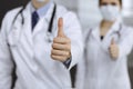 Unknown man-doctor and woman standing straight as a team and showing Ok sign with thumbs up in modern clinic. Medicine Royalty Free Stock Photo