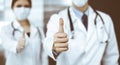 Unknown man-doctor and woman standing straight as a team and showing Ok sign with thumbs up in modern clinic. Medicine Royalty Free Stock Photo