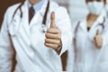 Unknown man-doctor and woman standing straight as a team and showing Ok sign with thumbs up in modern clinic. Medicine Royalty Free Stock Photo