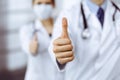 Unknown man-doctor and woman standing straight as a team and showing Ok sign with thumbs up in modern clinic. Medicine Royalty Free Stock Photo