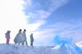 An unknown man squats next to four children in winter in a fog in the sun looking at the colored blue smoke