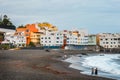 Unknown people are walking and relaxing on the beach with colour houses in the