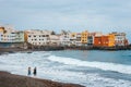 Unknown people are walking and relaxing on the beach with colour houses in the
