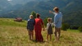 Family walking down green mountain hill back view. Parents with kids relax. Royalty Free Stock Photo