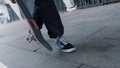 Unknown skater going to workout. Man feet in sporty shoes walking on street. Royalty Free Stock Photo