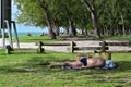 Unknown tourist in swimsuit and sleeping in the shade on the grass by the beach.