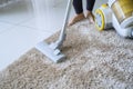 Unknown woman cleans carpet with a vacuum cleaner