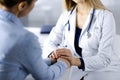 Unknown woman-doctor is holding her patient`s hands to reassure the patient, discussing current health examination