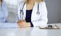 Unknown woman-doctor is holding her patient`s hands to reassure a patient, while sitting together at the desk in the