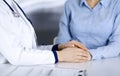 Unknown woman-doctor is holding her patient`s hands to reassure a patient, while sitting together at the desk in the