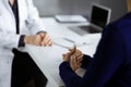 Unknown woman-doctor is talking to her patient about her diagnosis, while sitting together at the desk in the cabinet in Royalty Free Stock Photo