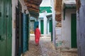 Unknown woman in national clothes on the old street in Tetouan Medina quarter in Northern Morocco. A medina is typically walled,