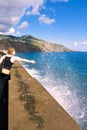 Unknown woman, reaching out to catch the water droplets splashing in the waves on a beach breakwater