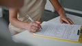 Woman hands signing papers sitting at table close up. Girl writing documents. Royalty Free Stock Photo