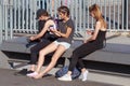 BARCELONA, SPAIN - MAY 16, 2017: Unknown young girls sitting on a bench in center of Barcelona in Port Vell at sunny day