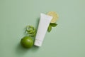 An unlabeled tube in white color displayed with Lime slices and peel Royalty Free Stock Photo