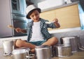 Unleashing an epic drum solo. Shot of a happy little boy playing drums with pots on the kitchen floor while wearing a Royalty Free Stock Photo