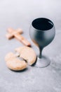 Unleavened bread, chalice of wine, wooden cross on grey background. Christian communion for reminder of Jesus sacrifice. Easter Royalty Free Stock Photo