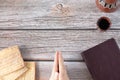 Unleavened bread matzo, a cup of wine, praying hands, and closed Holy Bible Book on a wooden table