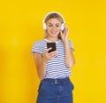 Unlimited music app. Smiling girl with headphones listening to the music on her phone on a yellow background Royalty Free Stock Photo