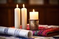 unlit shabbat candles with a torah and prayer shawl in the background