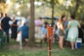 Unlit tiki torch or citronella lantern at garden party with guests out of focus in background Royalty Free Stock Photo