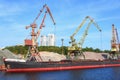 Unloading of the barge with crushed stone port cranes in the port.