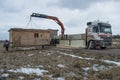 Unloading with a crane manipulator of a construction shed on a rural site for the arrangement of a construction site