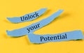 UNLOCK YOUR POTENTIAL text on a blue pieces of paper on yellow background, business concept Royalty Free Stock Photo