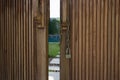 Unlocked metal chain on wooden doors with garden behind