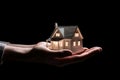 Unlocking the Dream: A Hand Holding a Model Home Against a Mysterious Backdrop