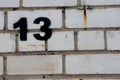 Unlucky unfortunate number thirteen painted black on a white brick wall