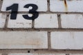 Unlucky unfortunate number thirteen painted black on a white brick wall