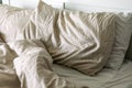 An unmade bed with pillows, sheets, and a blanket, side view