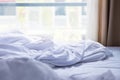 Unmade bed with white sheet and blanket, bright morning light co Royalty Free Stock Photo