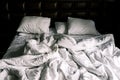 Unmade double empty bed with white linens. Sheets and pillows in the apartment or hotel after a night`s sleep. Royalty Free Stock Photo