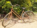 A unmaintained old orange bicycle