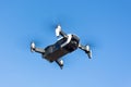 Unmanned drone flies through the air against the blue sky.