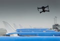 Unmanned drone flying near row of commercial airplanes at airport