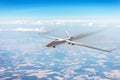 Unmanned military aircraft flies high in the sky at high speed over fields, blue sky clouds